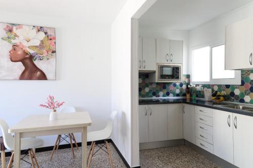 a kitchen with white cabinets and a table with chairs at Los Arenales Agaete in Agaete