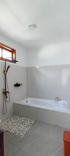 a white bathroom with a bath tub in a room at Villa Panda in Lovina
