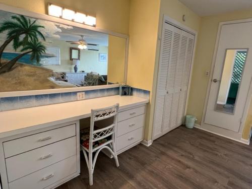 a bathroom with a vanity with a mirror and a chair at The Green Iguana Hotel in Charlotte Amalie