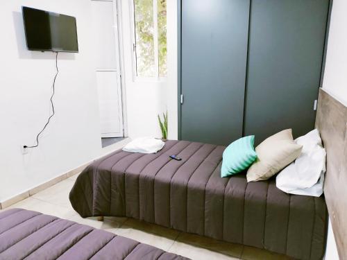 1 dormitorio con 1 cama con almohadas y TV en Aqua Suites, en Oaxaca City