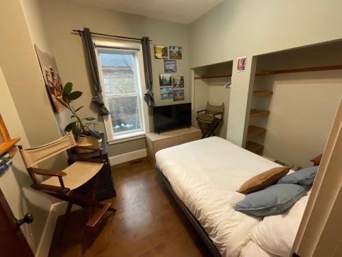 Schlafzimmer mit einem Bett, einem TV und einem Stuhl in der Unterkunft Chalet Au Bon Pain by Fernie Lodging Company in Fernie