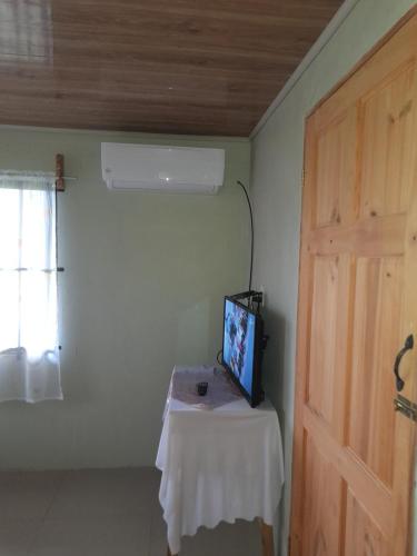 a room with a table with a tv and a door at Casa Lapas. in Aguas Zarcas