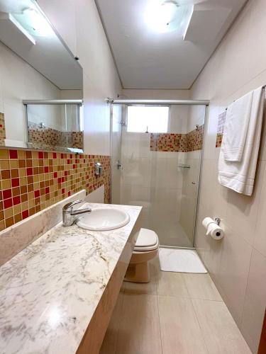 a bathroom with a sink and a shower and a toilet at Regente Hotel in Pato Branco