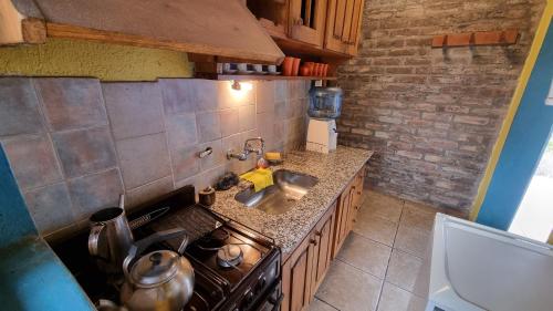Una pequeña cocina con estufa y fregadero. en Cabañas La Ofelia, en Potrerillos