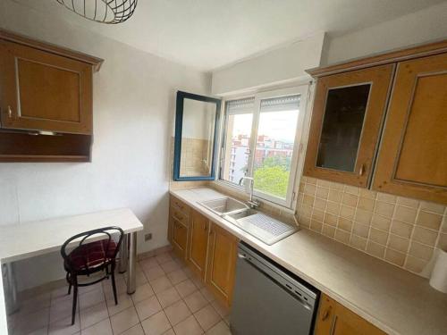 uma cozinha com uma cadeira, um lavatório e uma janela em Appartement centre ville tout confort et spacieux em Cergy