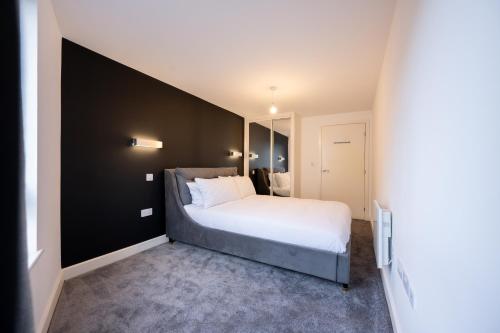 1 dormitorio con 1 cama grande y pared negra en Luxury Apartment by Ocean Village Marina en Southampton