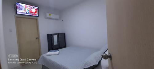 sypialnia z łóżkiem i telewizorem na ścianie w obiekcie LINDO APARTAMENTO CERCA AL CC ALAMEDAS w mieście Montería