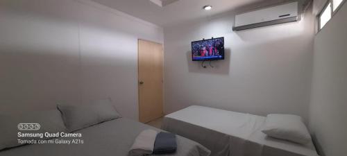 mały pokój z dwoma łóżkami i telewizorem na ścianie w obiekcie LINDO APARTAMENTO CERCA AL CC ALAMEDAS w mieście Montería