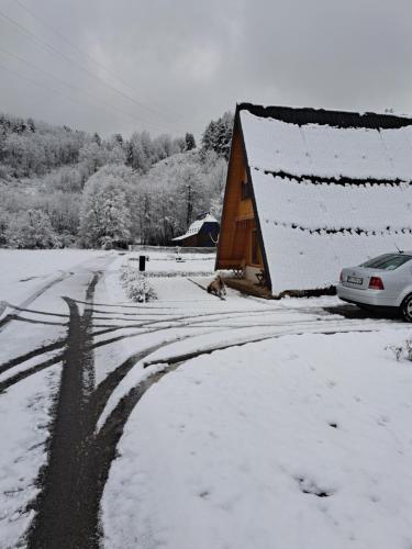 a house is covered in snow next to a road at Holiday Home Ella - Apartman Ella in Mokra Gora