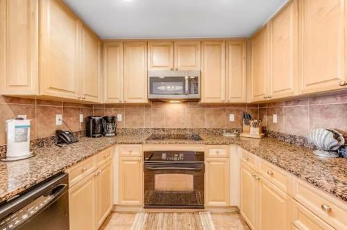 a kitchen with wooden cabinets and a microwave at Portofino Island P2-905 in Pensacola Beach