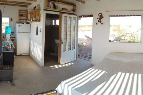 a room with a bed and a kitchen with a refrigerator at Mandalei, Refugio De Mar in Las Grutas