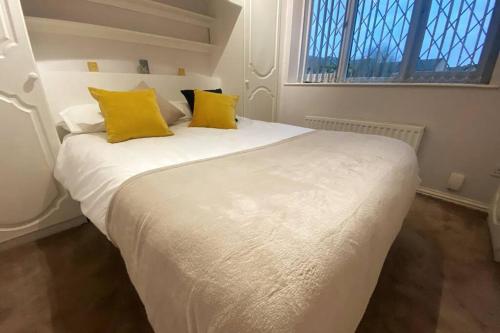 een wit bed met gele kussens in een slaapkamer bij Boss Breaks-Luton in Luton