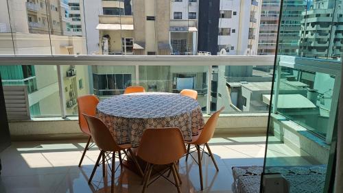 stół i krzesła siedzące wokół stołu na balkonie w obiekcie Apt Confort - Suíte c/ hidro - 9 min da praia a pé w mieście Itapema