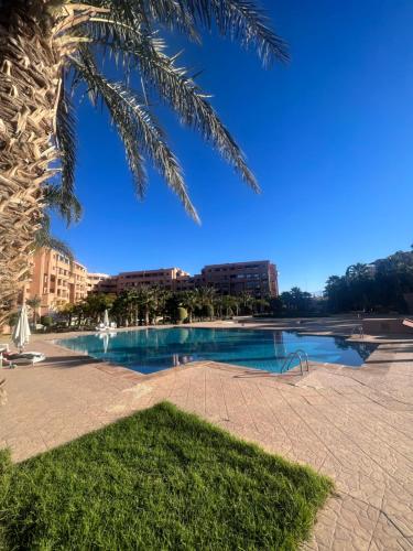 een zwembad in een park met een palmboom bij Appartement Hivernage M Avenue in Marrakesh