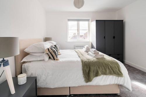 um quarto com uma cama grande com lençóis brancos e almofadas em Immaculate 2-Bed Apartment in Welwyn Garden City em Welwyn Garden City