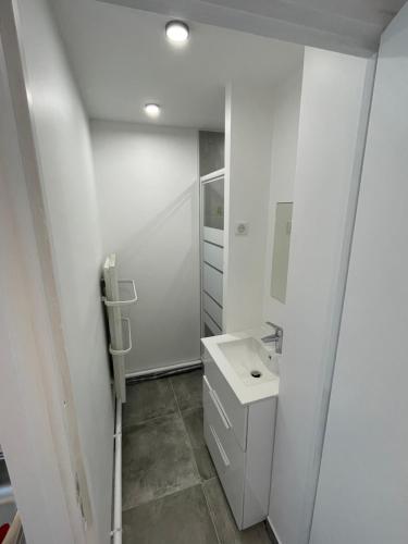 ein weißes Badezimmer mit einem Waschbecken und einem Spiegel in der Unterkunft Spacieux appartement Paris/Stade De France/CDG in La Courneuve