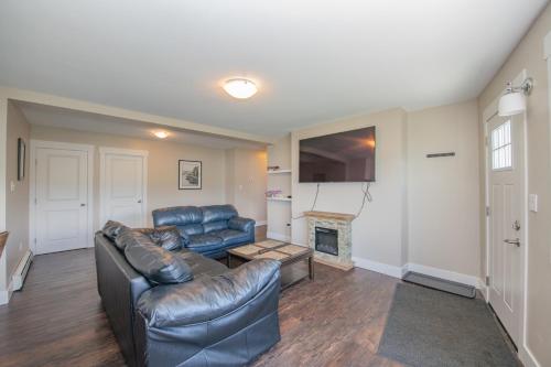 a living room with a leather couch and a fireplace at Lakeviews, big yard/deck, minutes to Silver Star/Golf/Wineries. in Vernon