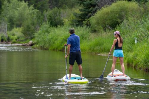 a man and a woman on paddle boards on a river at Snowmass Villas 3 plus loft in Snowmass Village