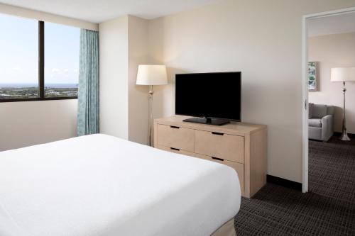 a hotel room with a bed and a flat screen tv at Embassy Suites by Hilton Tampa Airport Westshore in Tampa