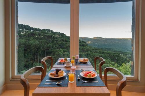una mesa de madera con platos de comida delante de una ventana en Golden Gramado Resort Laghetto en Gramado