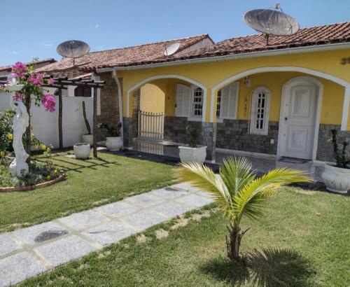 a yellow house with a palm tree in the yard at CASA EM PRAIA SECA in Araruama