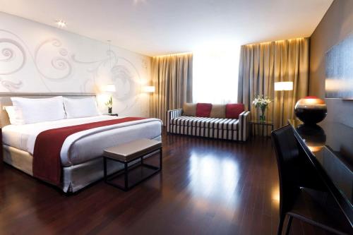 um quarto de hotel com uma cama e um sofá em NH Buenos Aires Tango em Buenos Aires