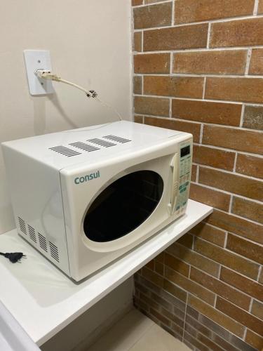a microwave sitting on a shelf next to a brick wall at Pousada Le Sorelle ap04 in Rosário do Sul