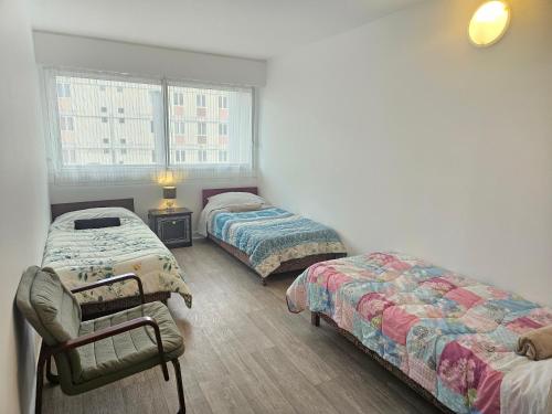 a bedroom with two beds and a chair and a window at Grand appartement 160m2 equipped for professionnal groups in Sarcelles