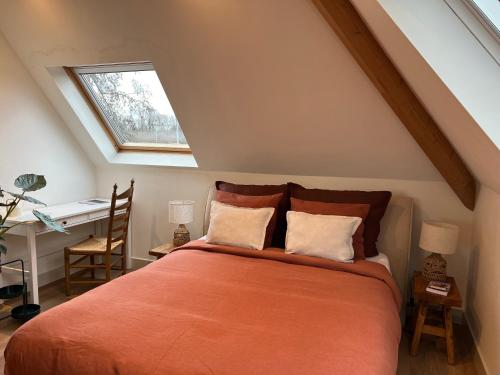 a bedroom with an orange bed with a desk and a window at Inn Het Nest in Amsterdam