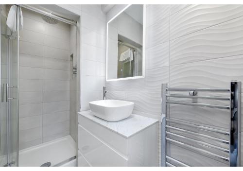 a white bathroom with a sink and a shower at Lovely 4 bedroom with Outdoor space! in London