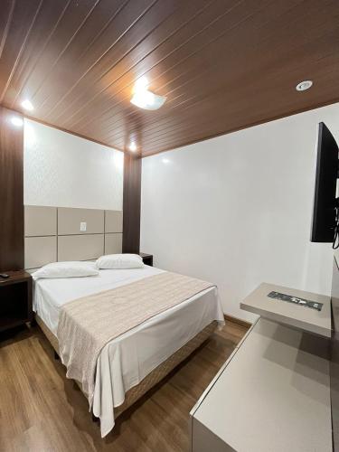 a bedroom with a bed and a desk and a television at Regente Hotel in Pato Branco