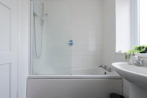 een witte badkamer met een douche en een wastafel bij Chingford charm great for families and contractors in Ponders End