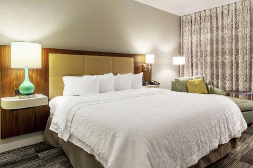 a hotel room with a large bed and a chair at Hampton Inn Minneapolis St. Paul-Woodbury in Woodbury