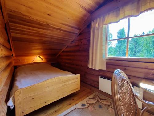 a small bed in a wooden room with a window at Aapishovi Chalet in Tapio