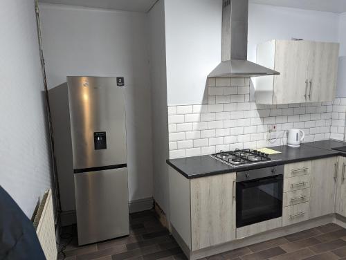 奧爾德姆的住宿－cozy double rm9，厨房配有不锈钢冰箱和炉灶。
