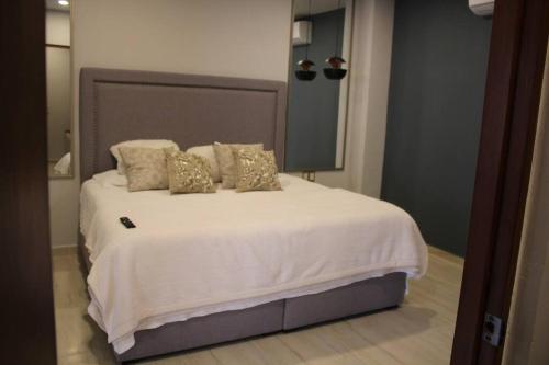 1 dormitorio con 1 cama blanca grande con almohadas de oro en Departamento entero de lujo en Los Mochis