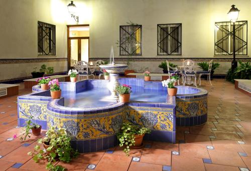 a room with a pool, a fountain, and a tub at Eurostars Regina in Seville