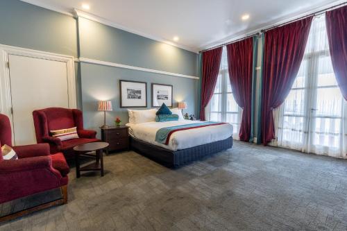 a hotel room with a bed and a chair at Grand Pacific Hotel in Suva