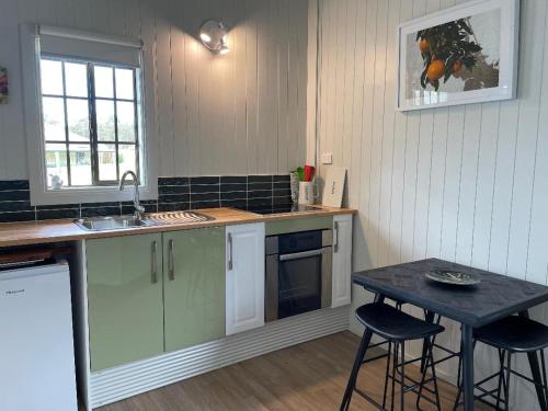 a kitchen with a sink and a table with stools at Straw House Farm B&B in Dalveen