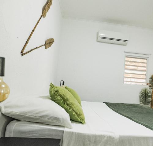 a white bedroom with a bed with green pillows at Landhuis Daniel - Plantation House in Tera Kora