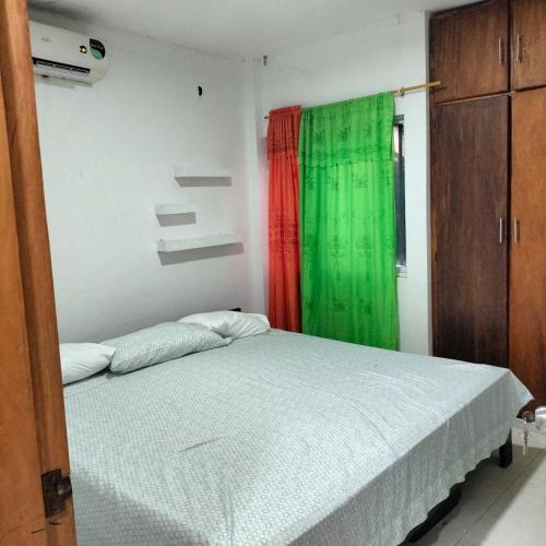 a bedroom with a bed with a green curtain at Alojamientos Fredys in El Socorro