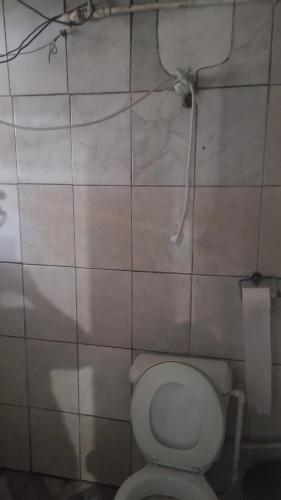 a bathroom with a toilet and a tiled wall at Casa grande sossego in Contagem