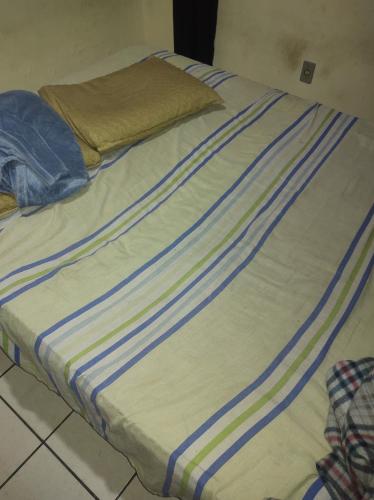 uma cama com riscas azuis e brancas em Casa grande sossego em Contagem