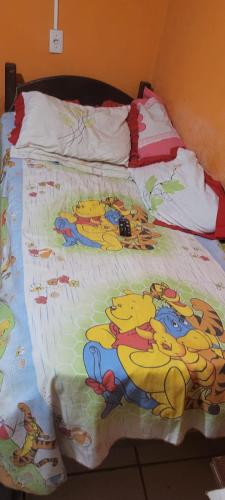 a bed with a bunch of disney cartoons on it at Casa grande sossego in Contagem