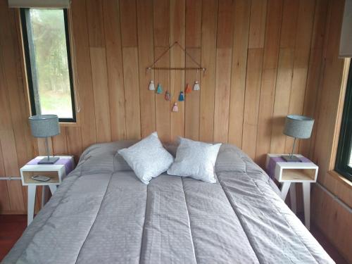 a bedroom with a bed with two nightstands and two lamps at Refugios del Monte in Villa Yacanto