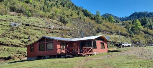 eine kleine Hütte auf einem Feld mit einem Berg in der Unterkunft Cabañas Rogelio in Liquiñe