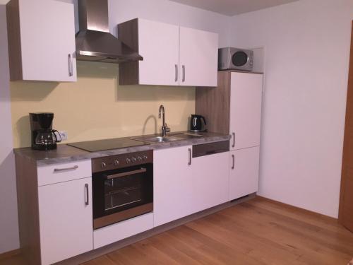 cocina con armarios blancos, fregadero y nevera en Appartement Heidi en Schladming