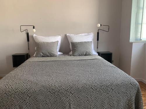 a bedroom with a bed with two pillows and two lamps at CASA DO PROFESSOR in Fuzeta