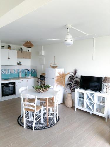 a white kitchen with a white table and chairs at Charmant studio vue mer SANS COUPURE D'EAU in Le Gosier