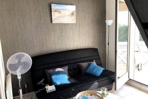 - un salon avec un canapé noir et des oreillers bleus dans l'établissement Duplex à Sète - Vue sur Mer, Piscine et Parking, à Sète